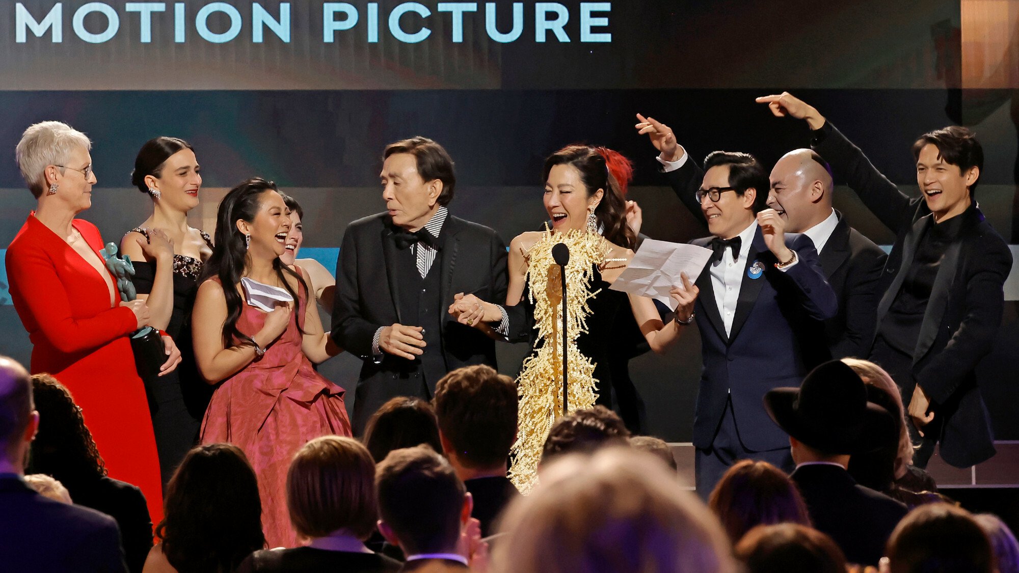 (L-R) Jamie Lee Curtis, Jenny Slate, Stephanie Hsu, Tallie Medel, James Hong, Michelle Yeoh, Ke Huy Quan, Brian Le, and Harry Shum Jr. accept the Outstanding Performance by a Cast in a Motion Picture award for
