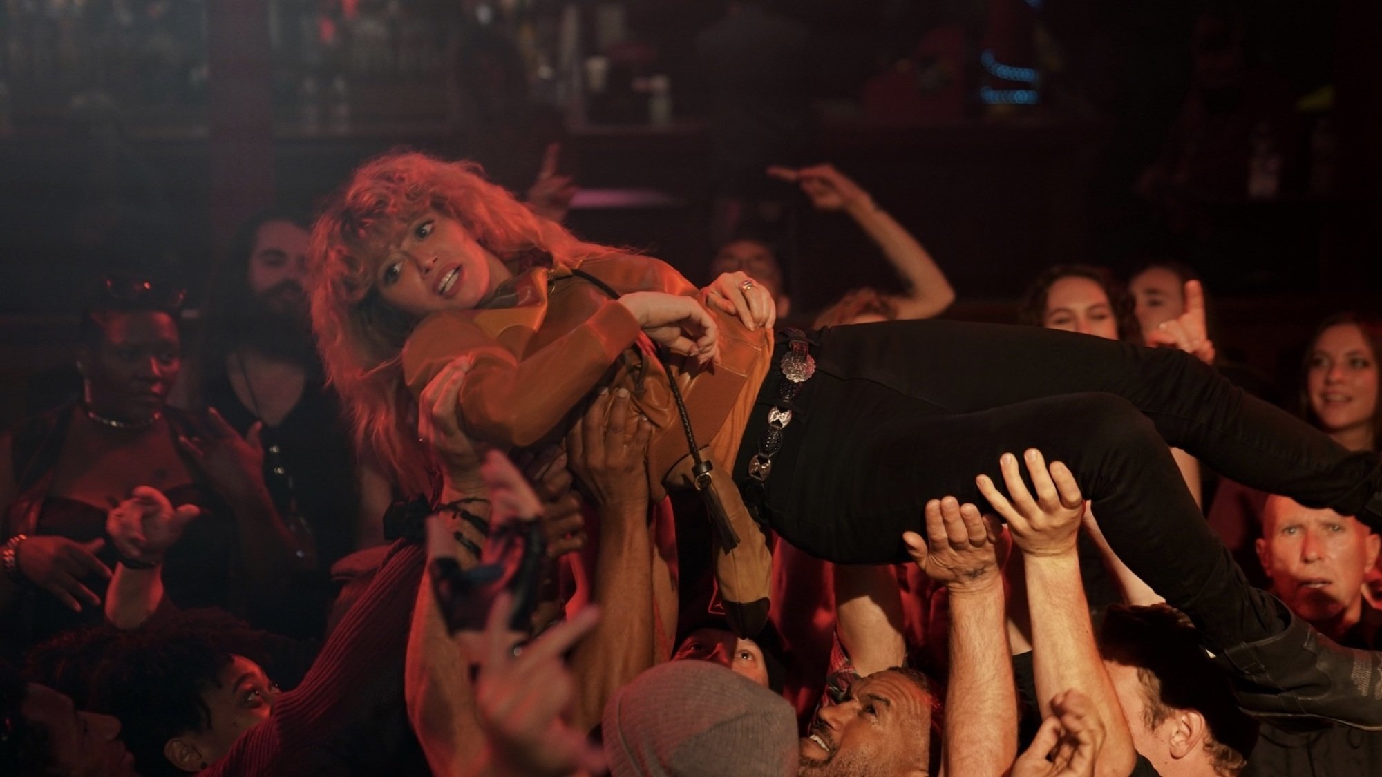 A woman crowdsurfs but doesn't look entirely happy about it.