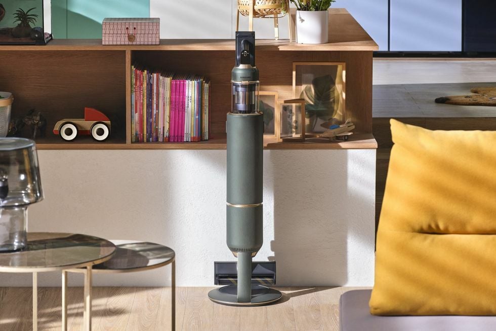 Green Samsung stick vacuum on dock in living space with shelves and furniture