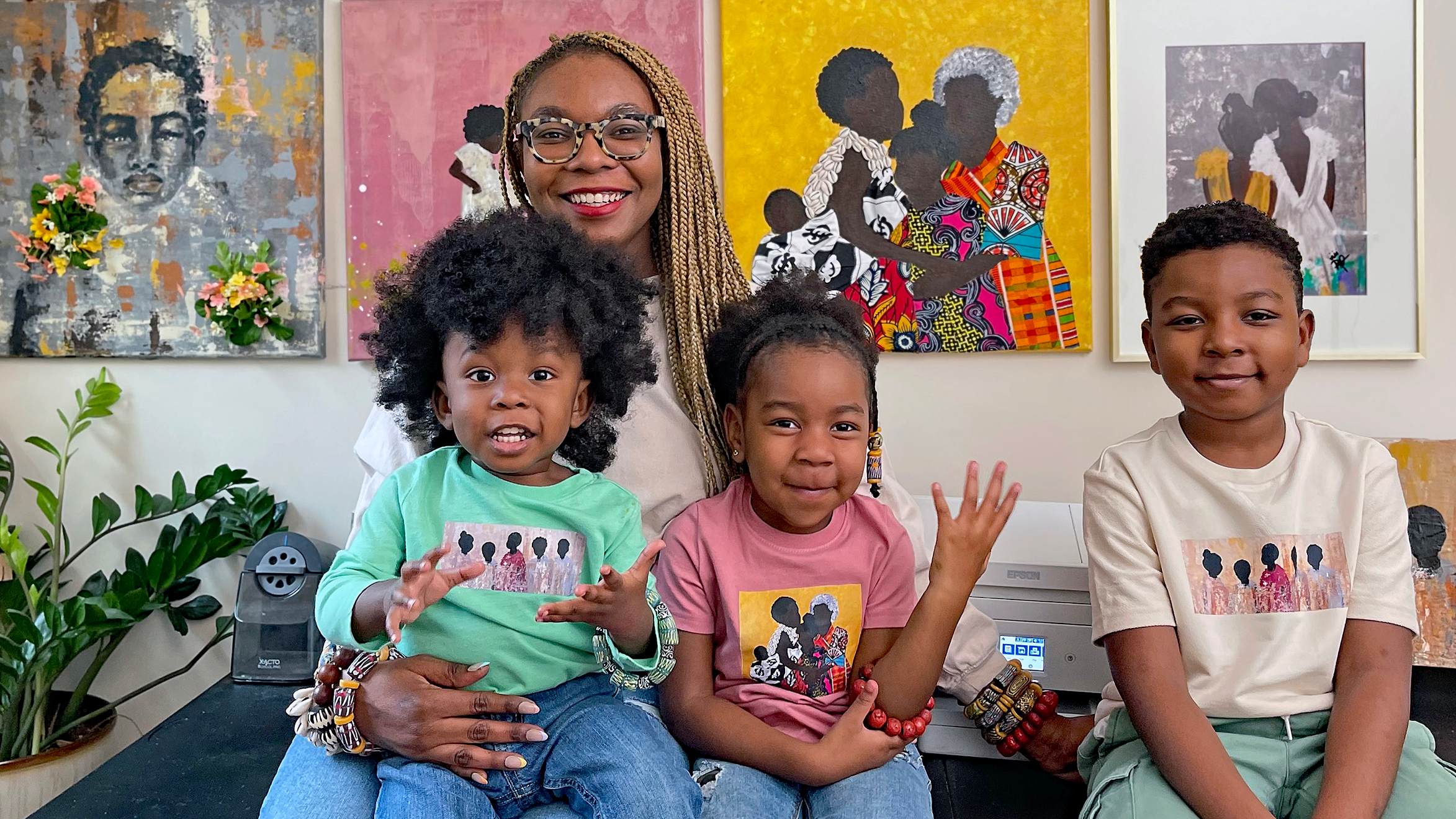 Artist Racquèl Dwomoh sits with her kids in front of her workstation