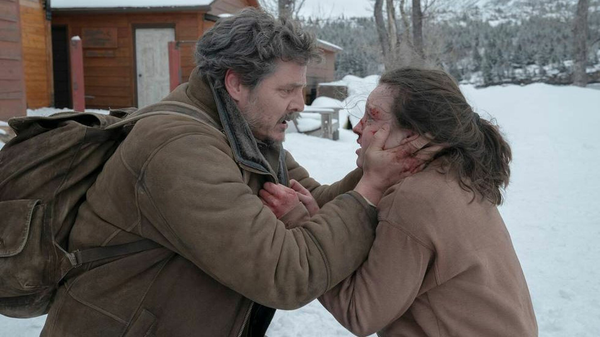 A man outside in the snow cradles the face of a young injured girl.