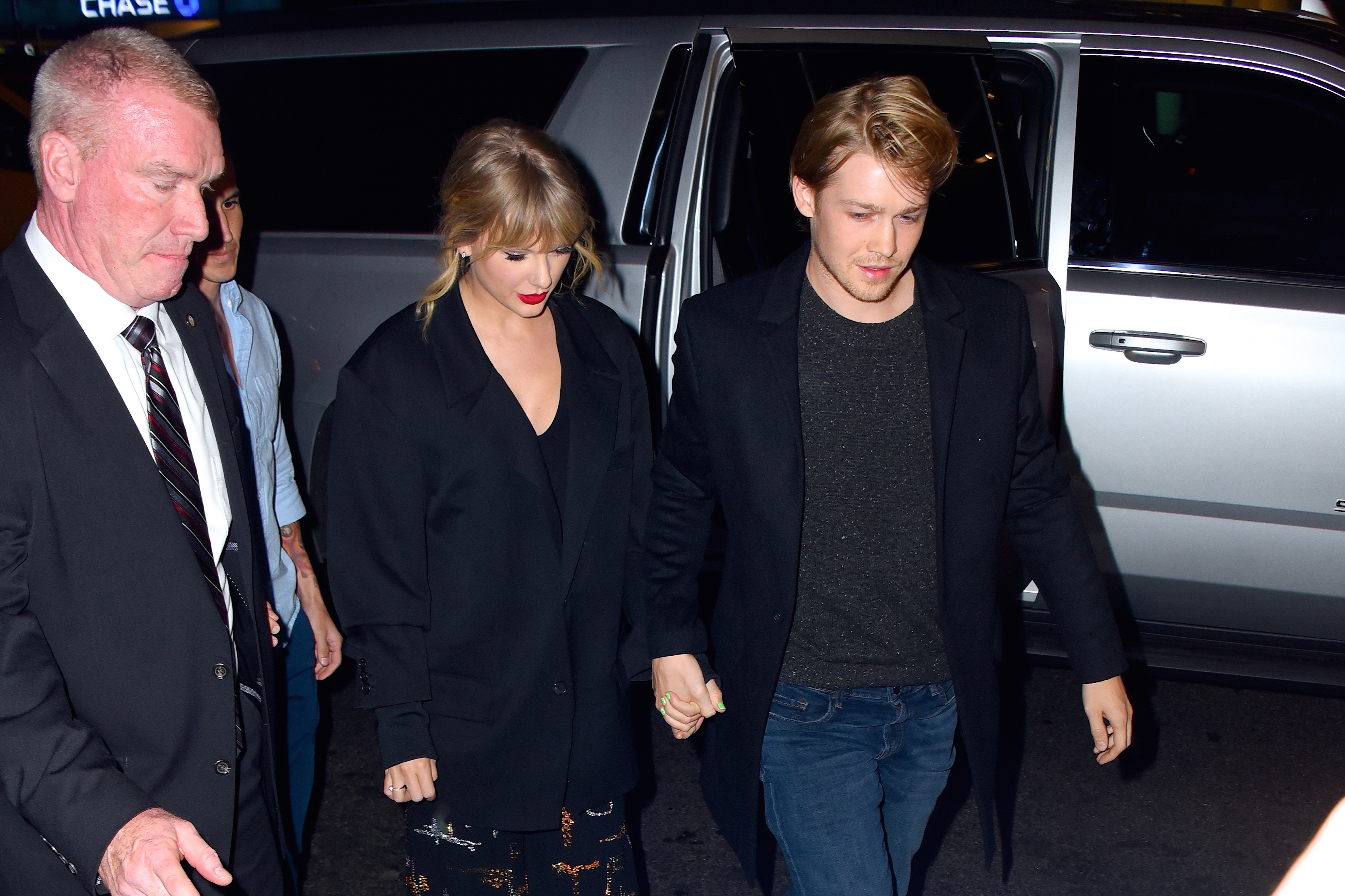 Taylor Swift and Joe Awlyn holding hands and looking down. 