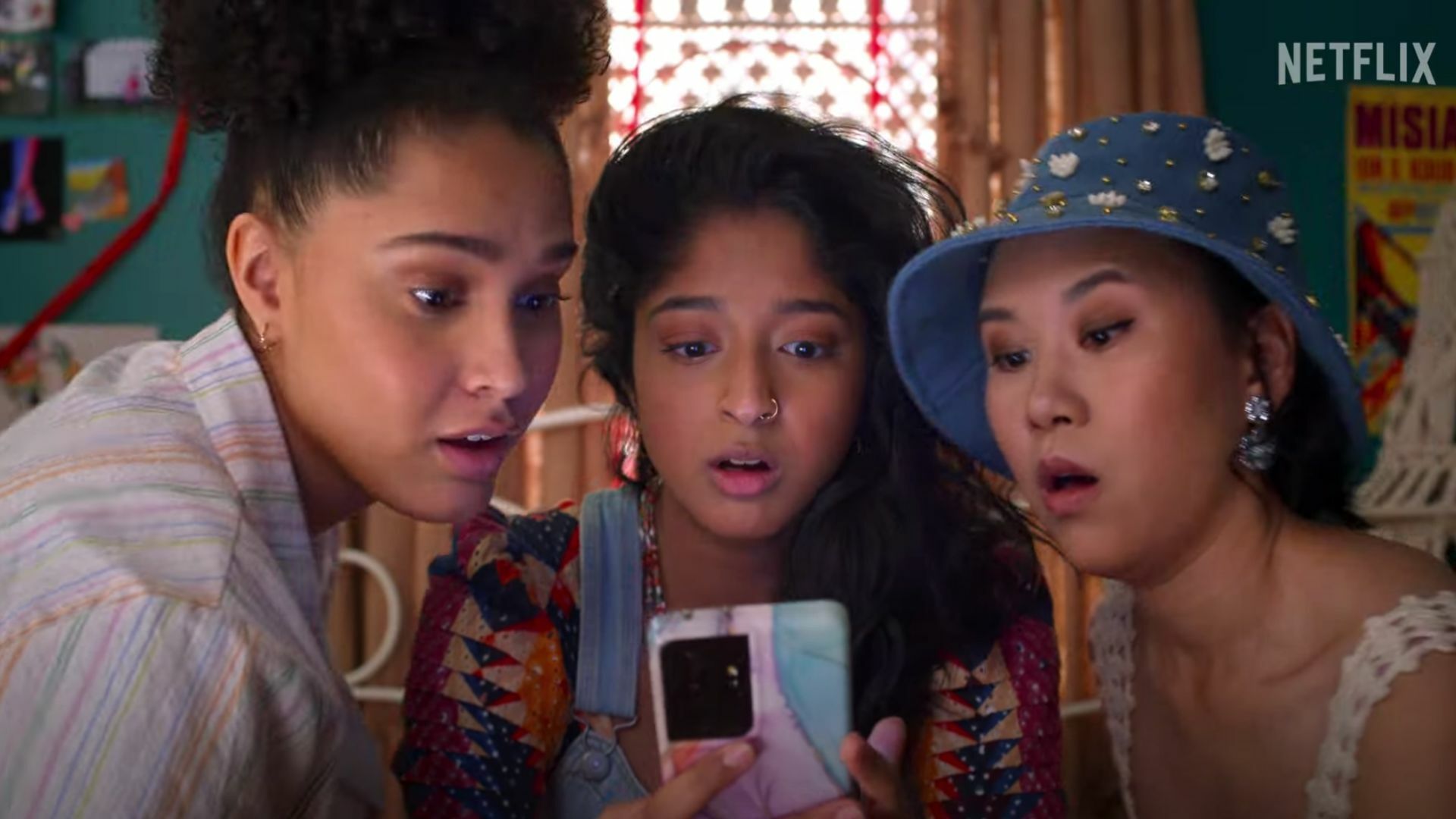 Devi (Maitreyi Ramakrishnan) and her two friends look over a phone in a still.
