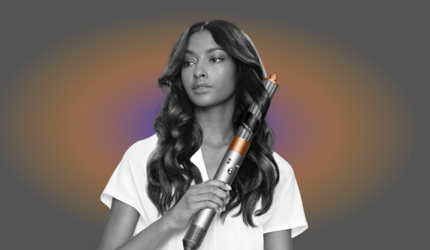 Person styling hair with Dyson Airwrap on gray background with orange light leak