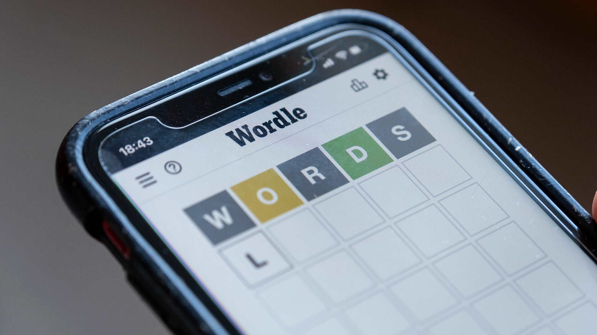 A close-up of a person playing Wordle on a smartphone.