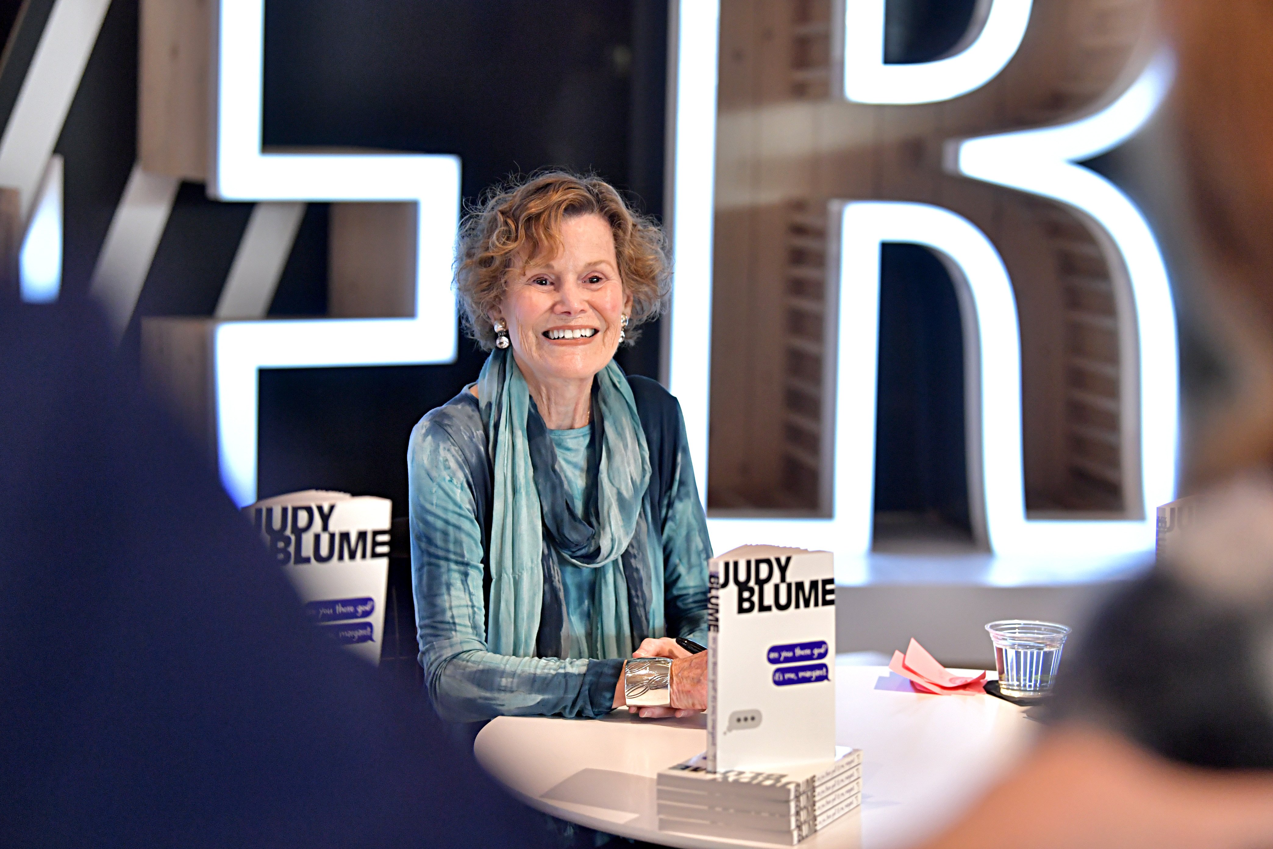 Blume smiles while seated at a table with her book