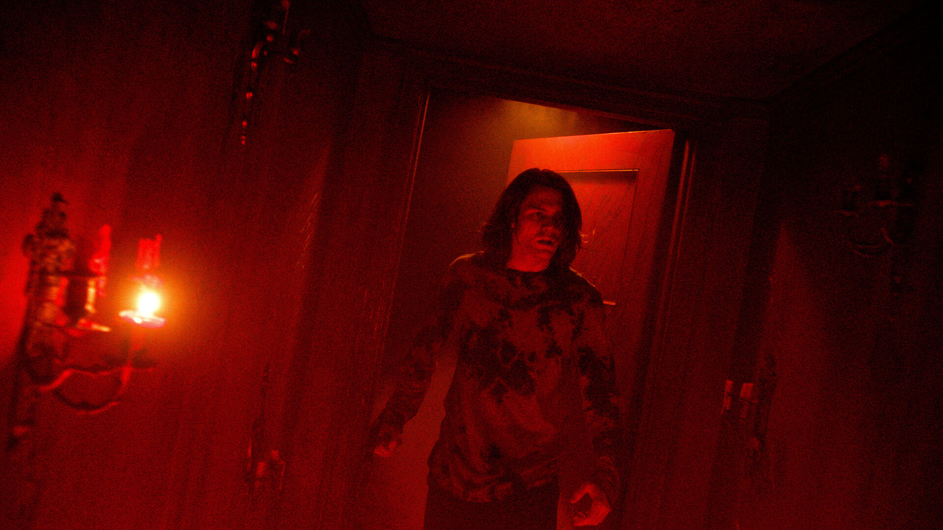 A young man walks into an entirely red lit room.