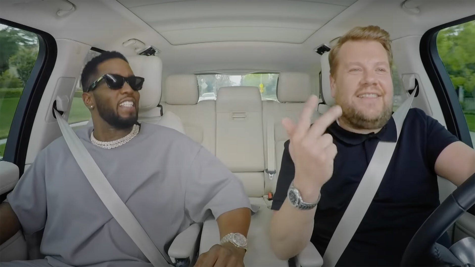 Two men sit in a car, laughing and talking.