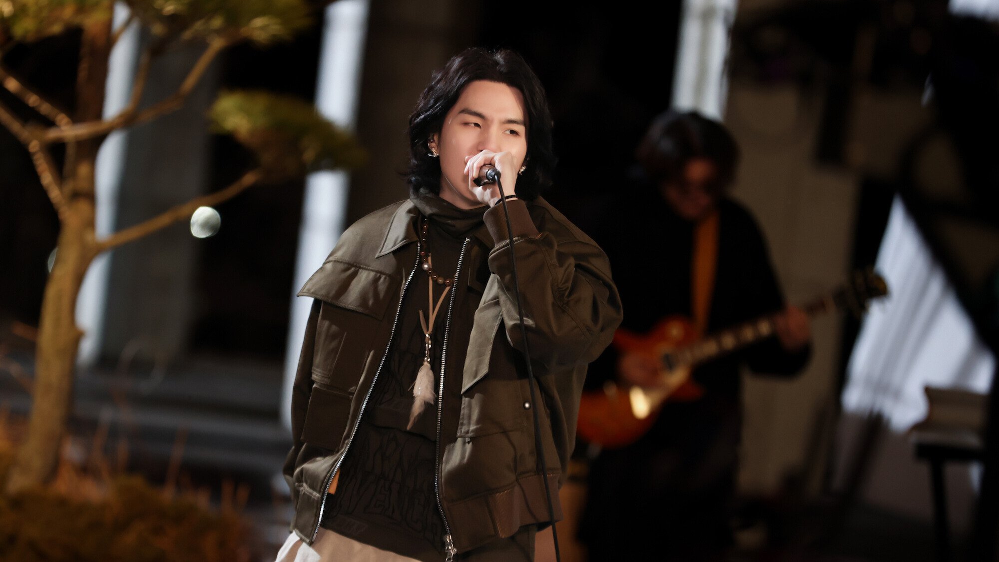 Suga of BTS performs, holding a microphone.
