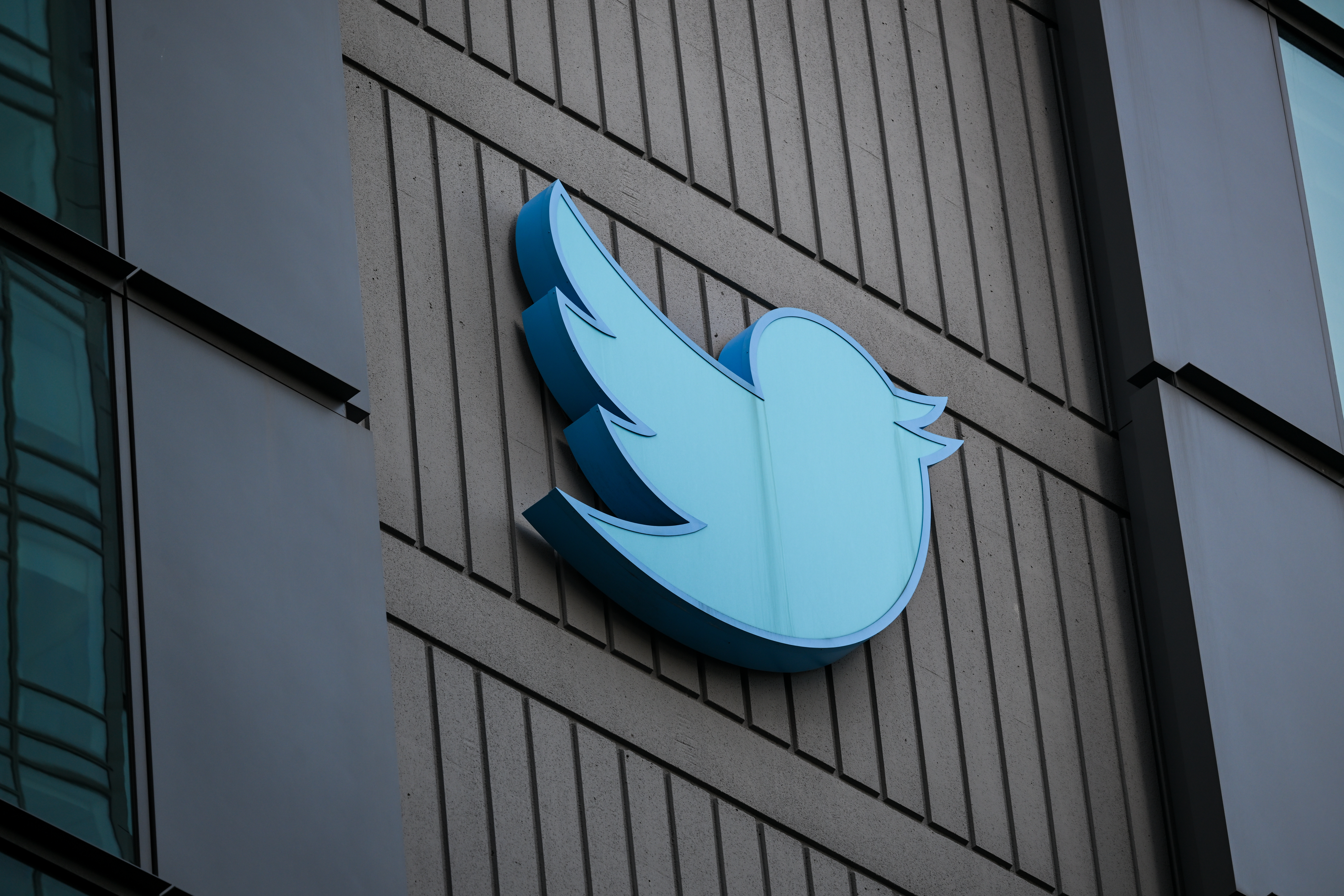 A blue Twitter bird logo on the side of a gray, concrete building.