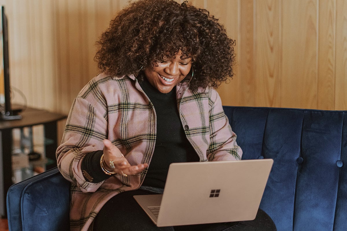 woman is smiling and looking at a laptop
