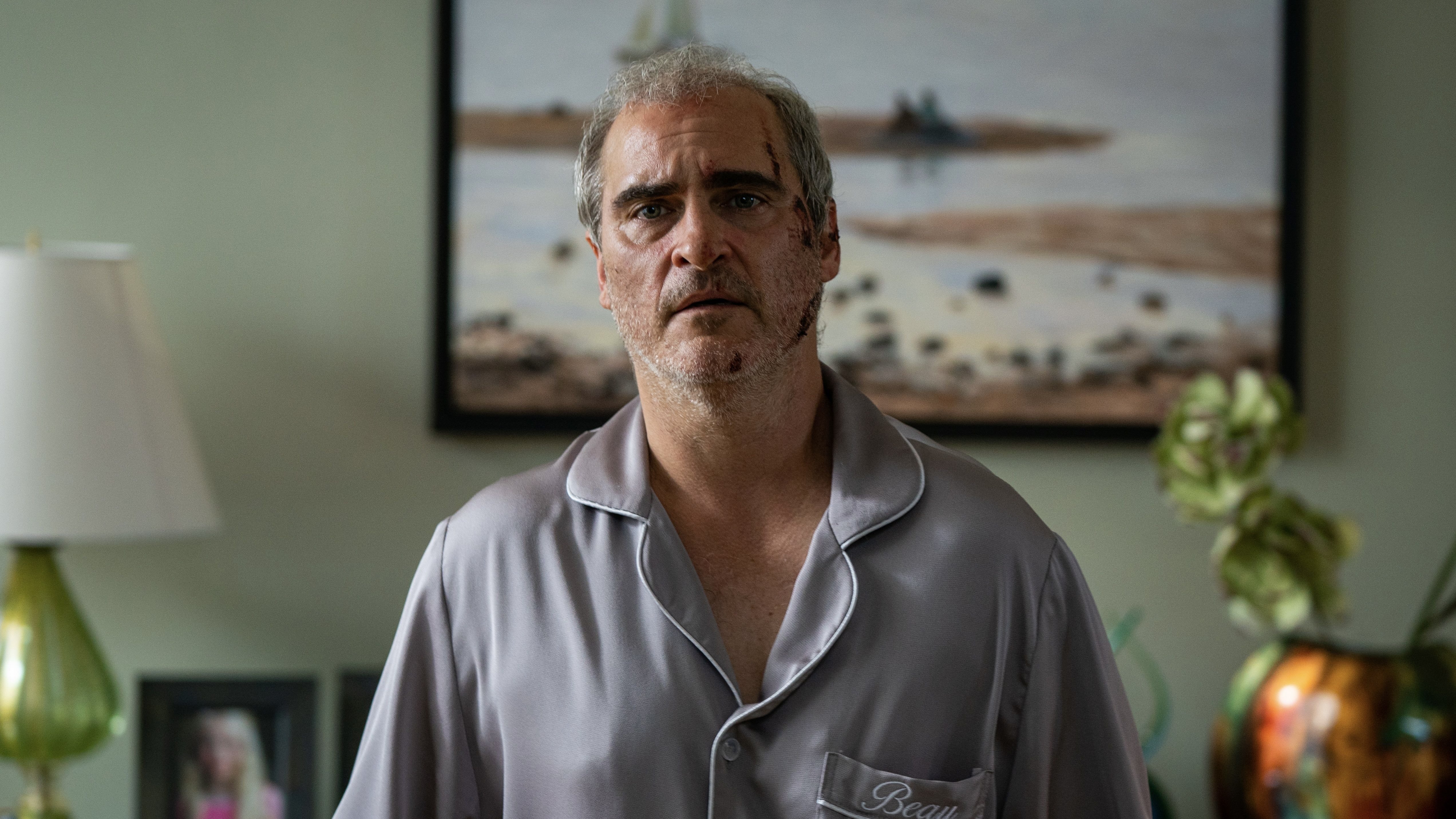 A man in grey pajamas with a bloody face.