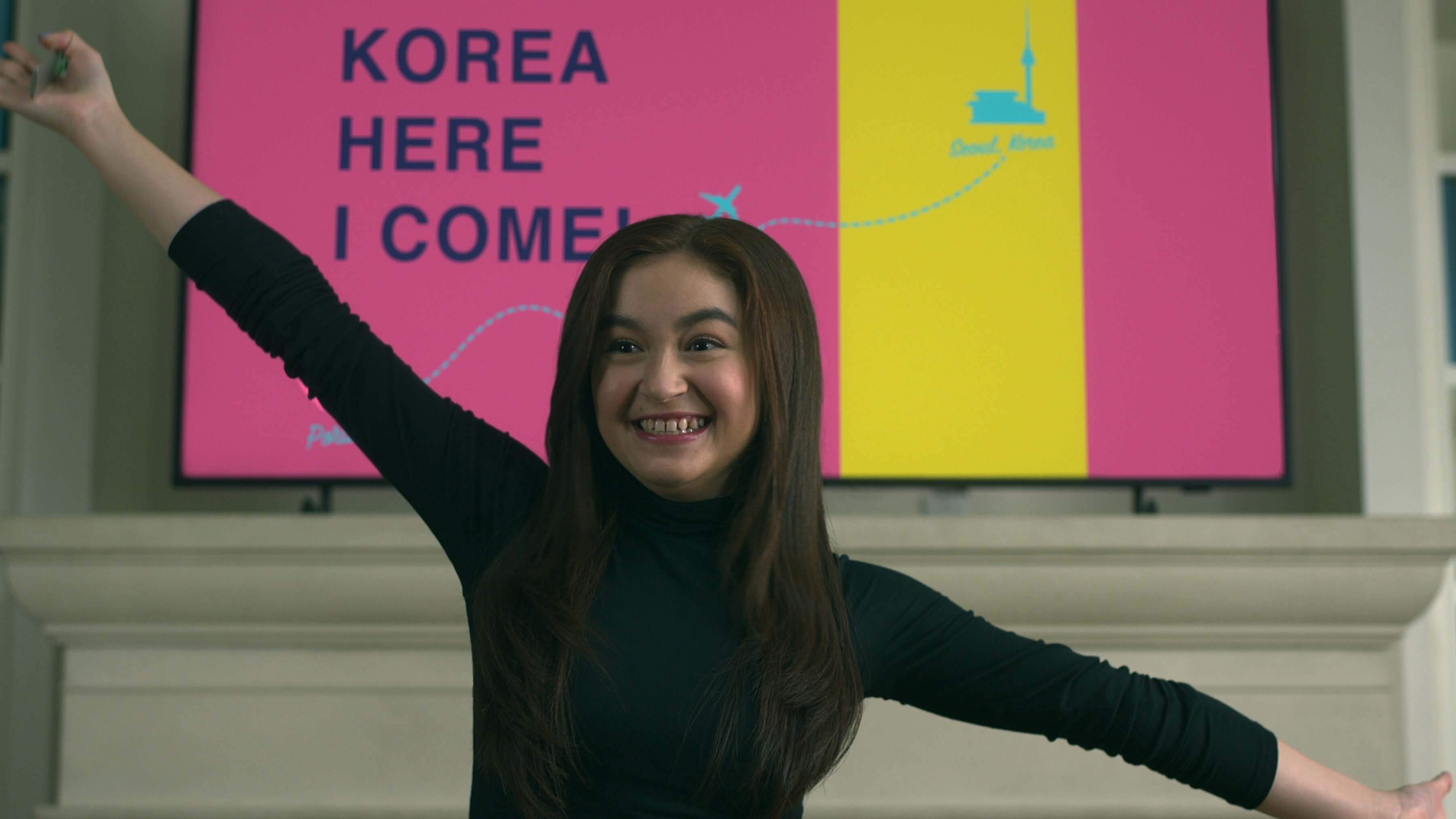 A young girl stands in front of a TV screen that reads