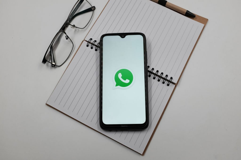 WhatsApp logo on phone screen on top of notepad