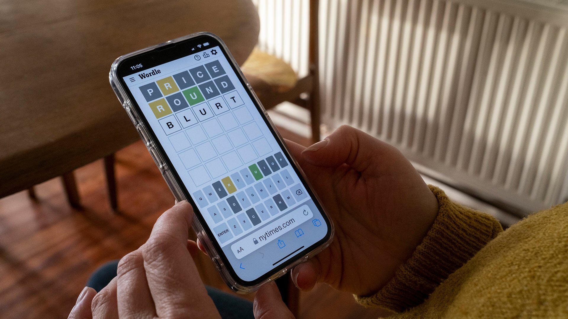 A close-up of a person playing Wordle on a smartphone.