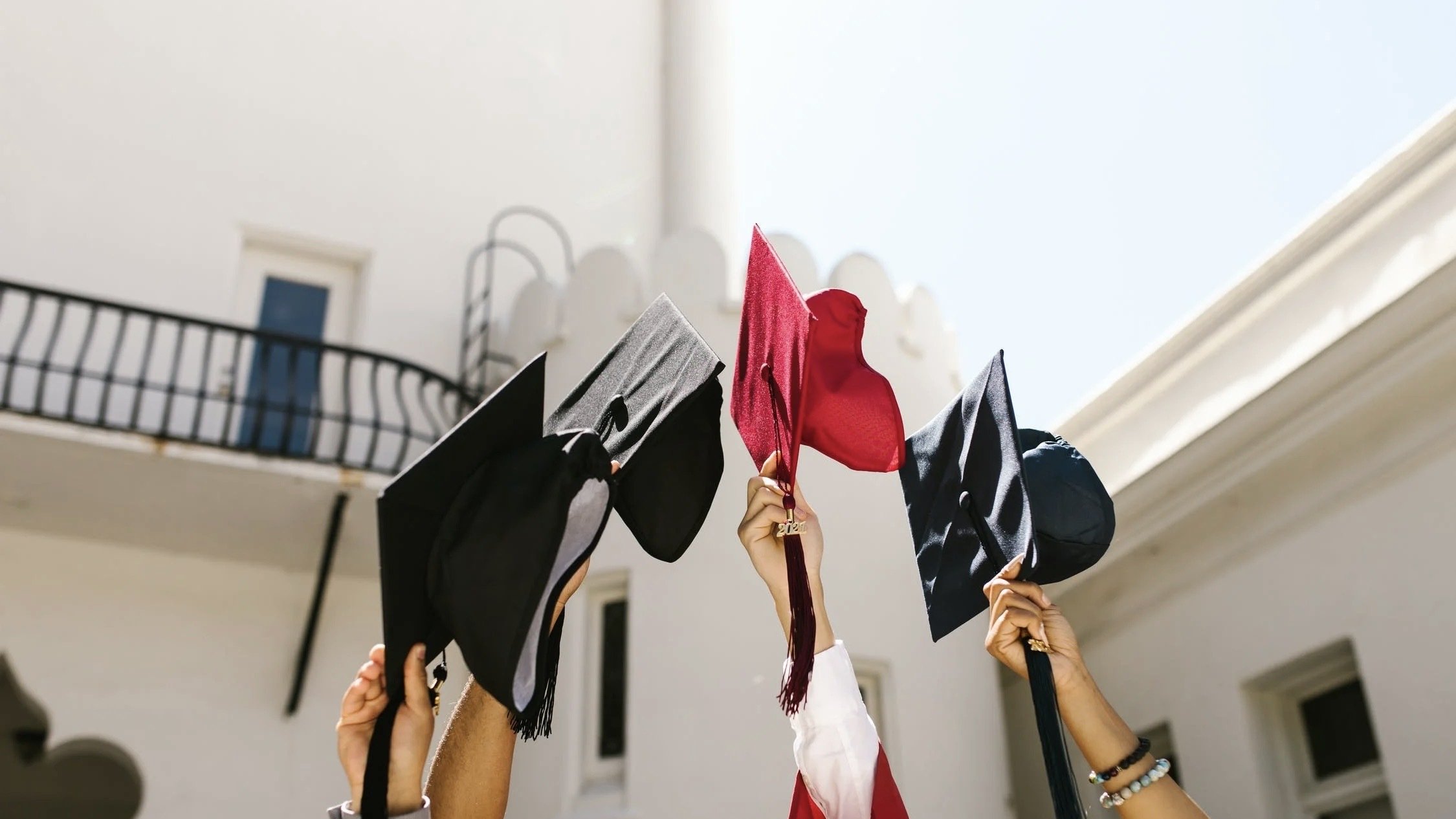People lifting their graduation caps to the sky.