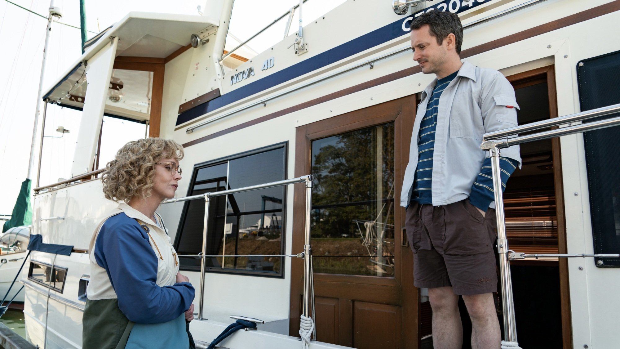 A woman greeting a man standing on the deck of a boat.