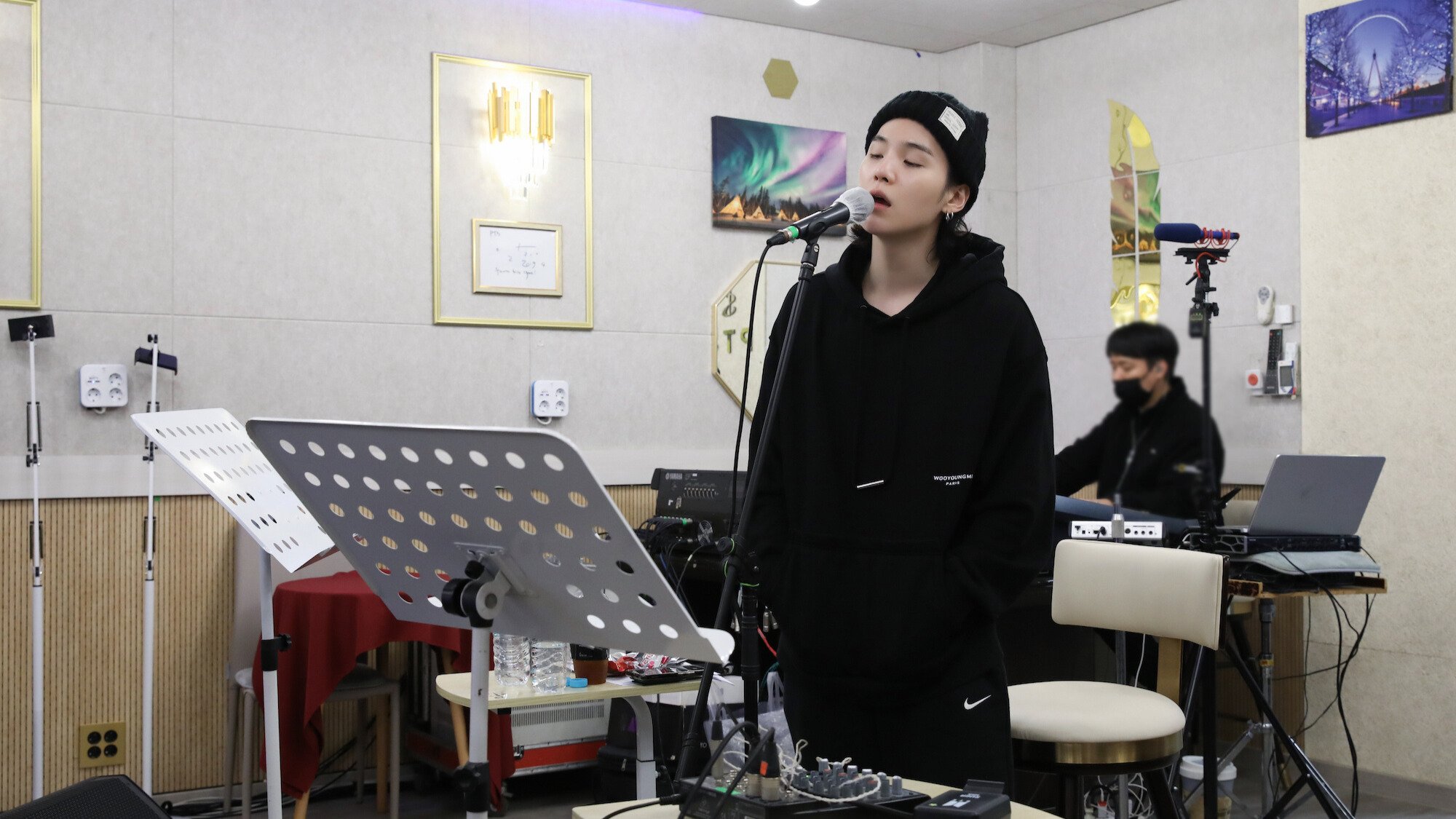 Suga from BTS records in a white studio room.