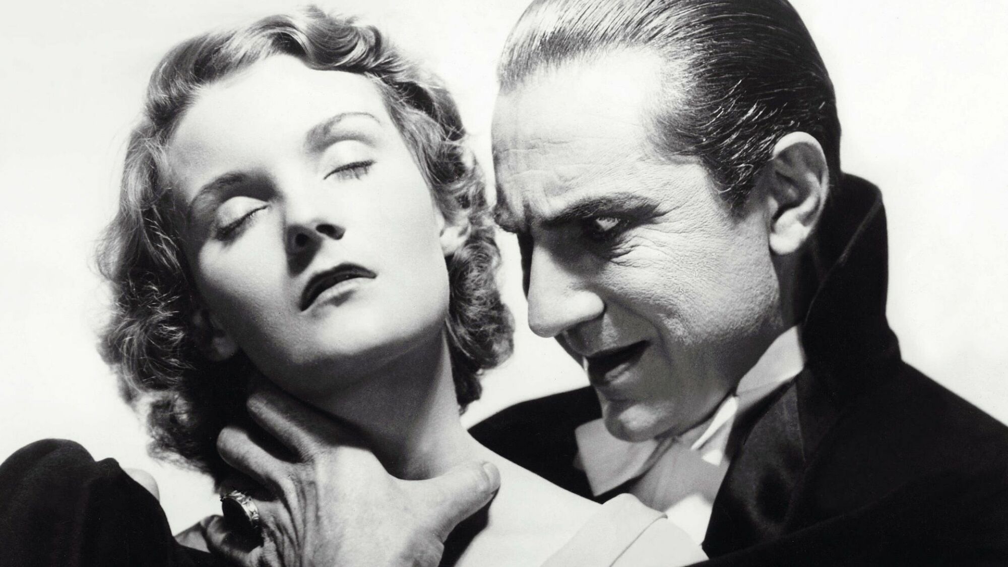 Bela Lugosi acts as Dracula, clutching the throat of Helen Chandler in a film still.