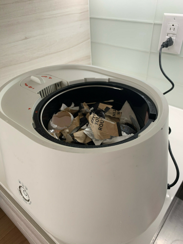 Lomi composter filled with food scraps, egg shells, and packaging before composting