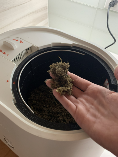 Hand holding fertilizer over Lomi composter bucket