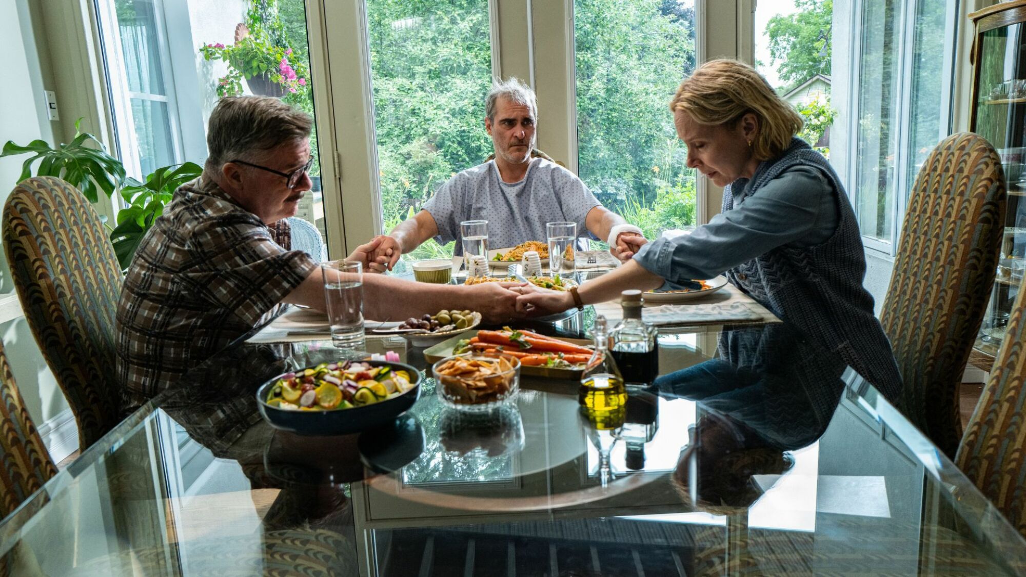 Nathan Lane, Joaquin Phoenix , and Amy Ryan hold hands in "Beau is Afraid."
