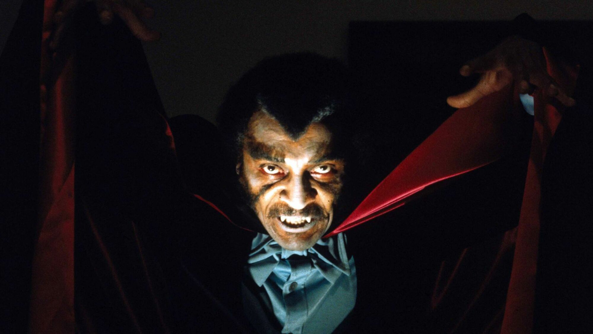 Actor William Marshall wearing a cape and baring fangs in the movie "Blacula."