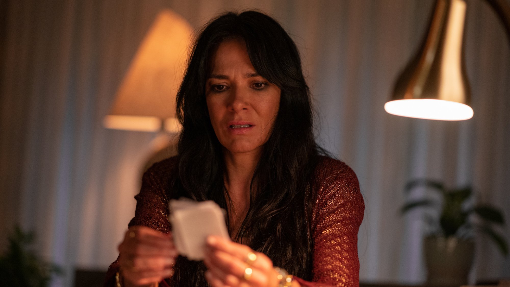 A woman stares in fear at a collection of notes in her office at night.