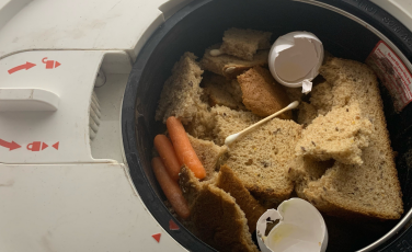 Lomi composter bucket filled with bread, egg shells, carrots, and cotton swab