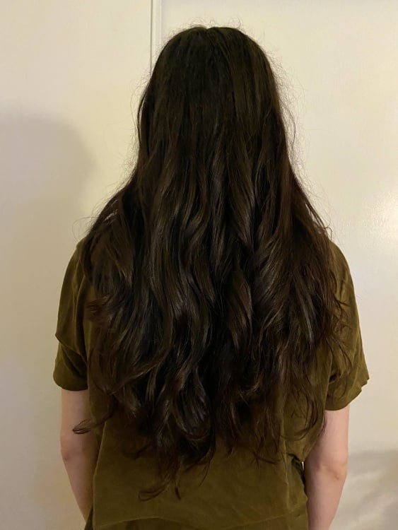 woman with long curled hair facing away from camera