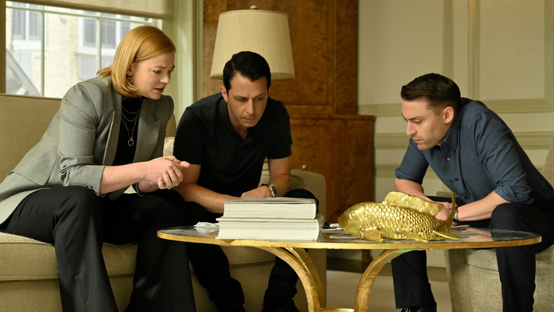 Two men and a woman wearing smart clothes sit around a table.