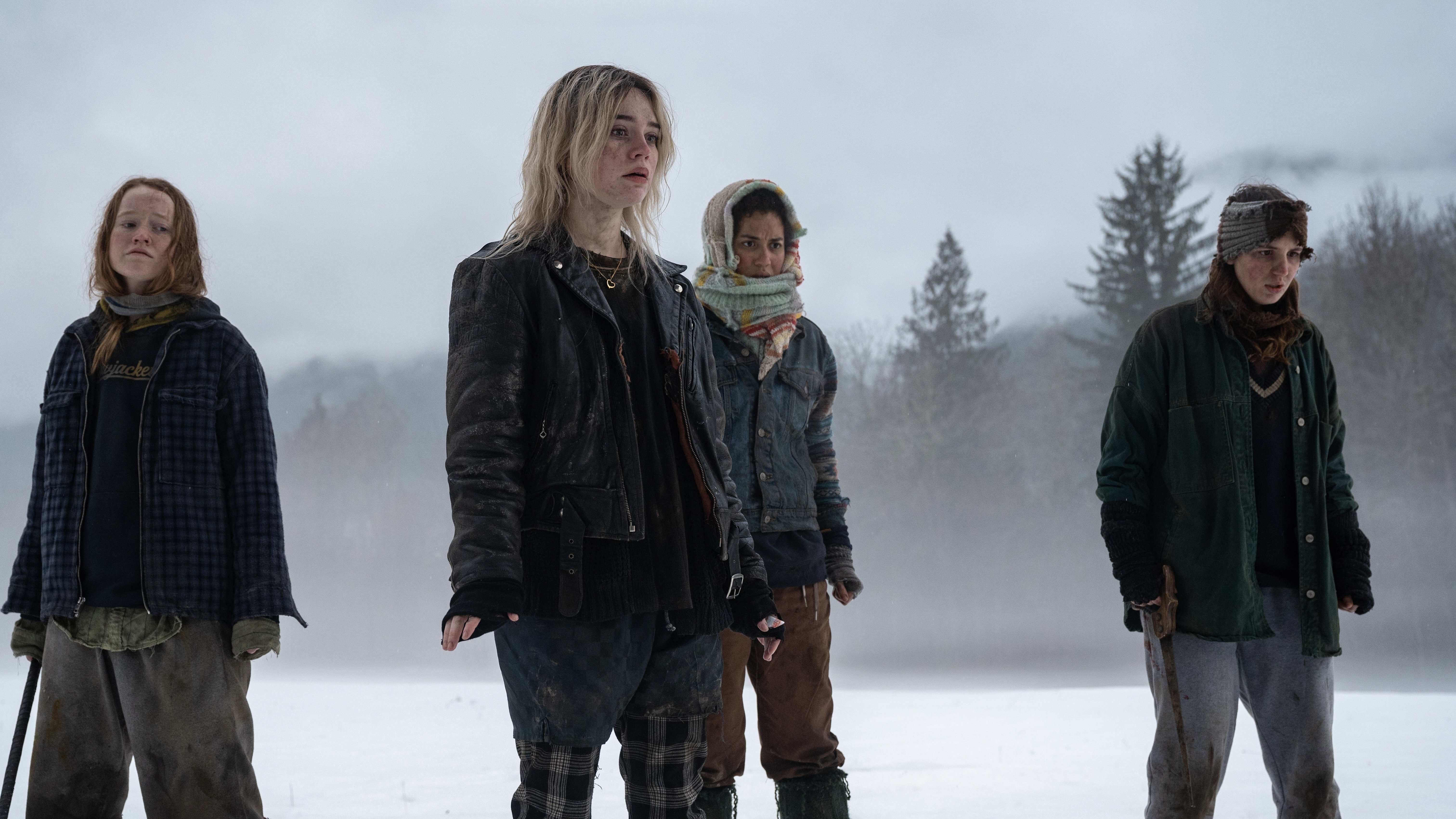 Four young women in winter clothes stand on a frozen river.