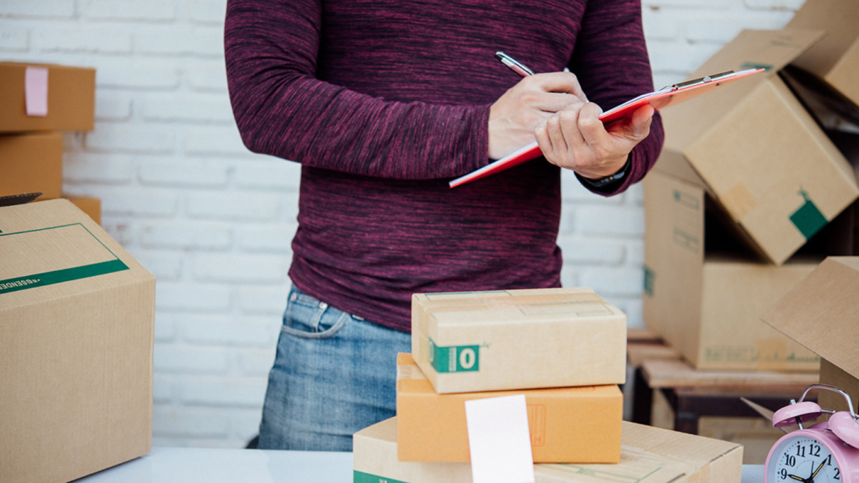 Man writing on pad surrounded by boxes