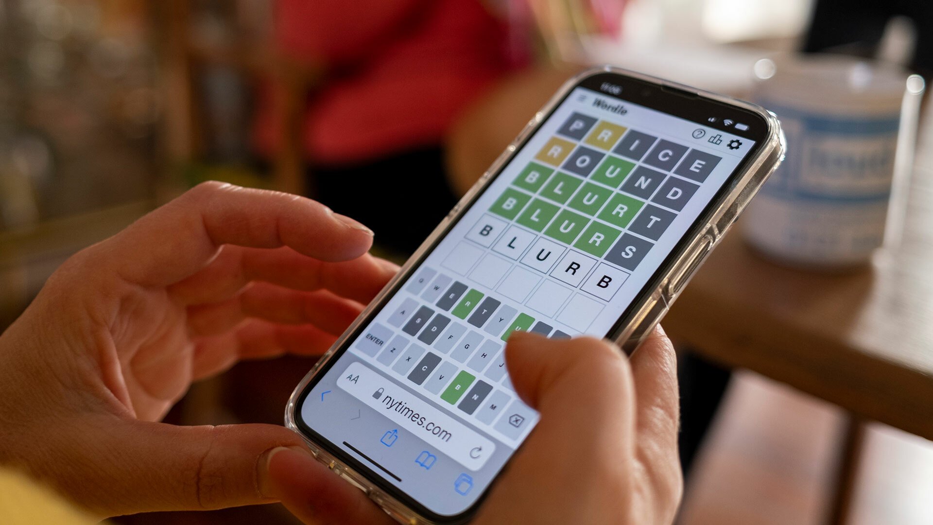 A close-up of a person playing Wordle on a smartphone.