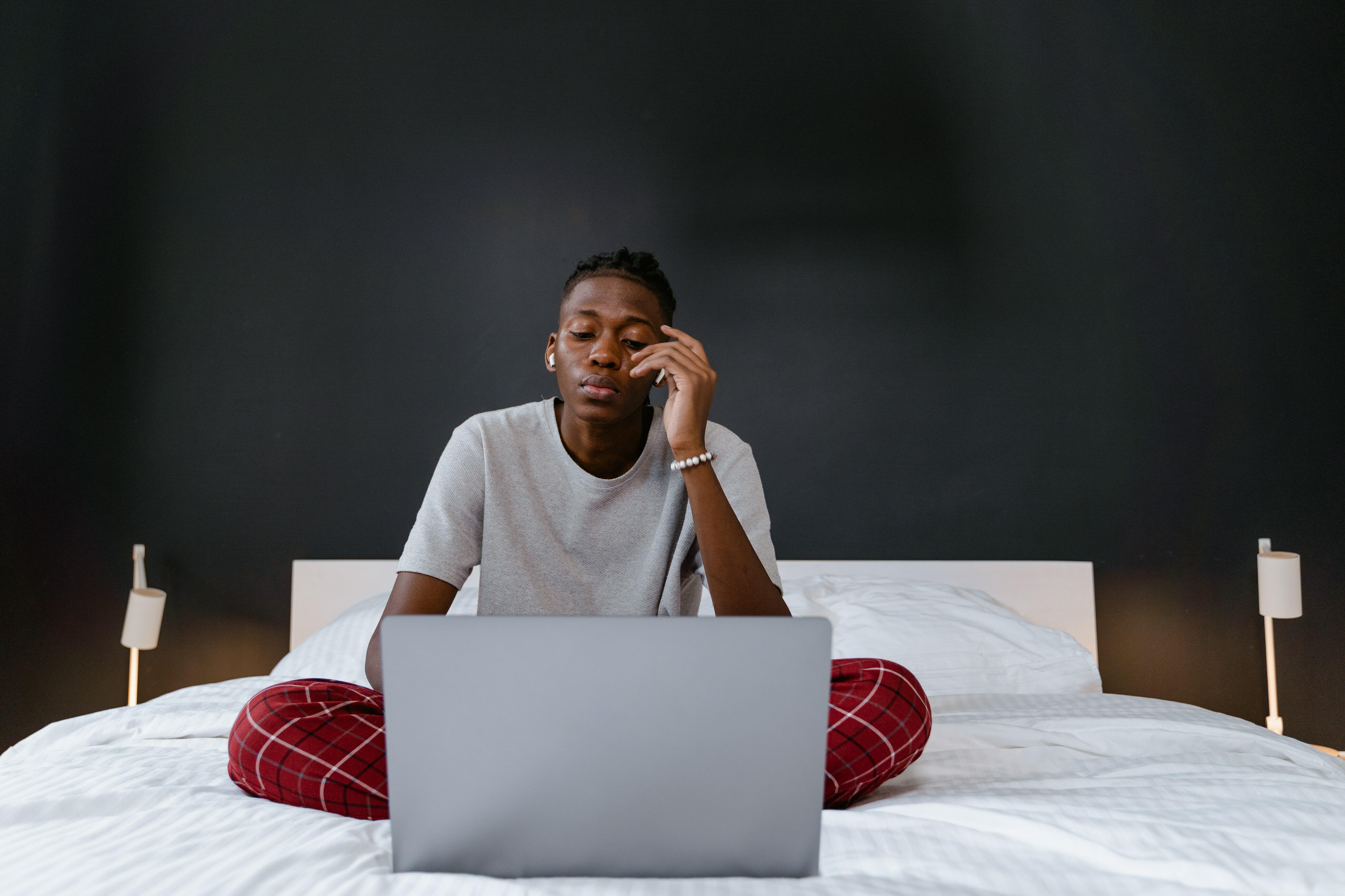 Man sat on bed with laptop