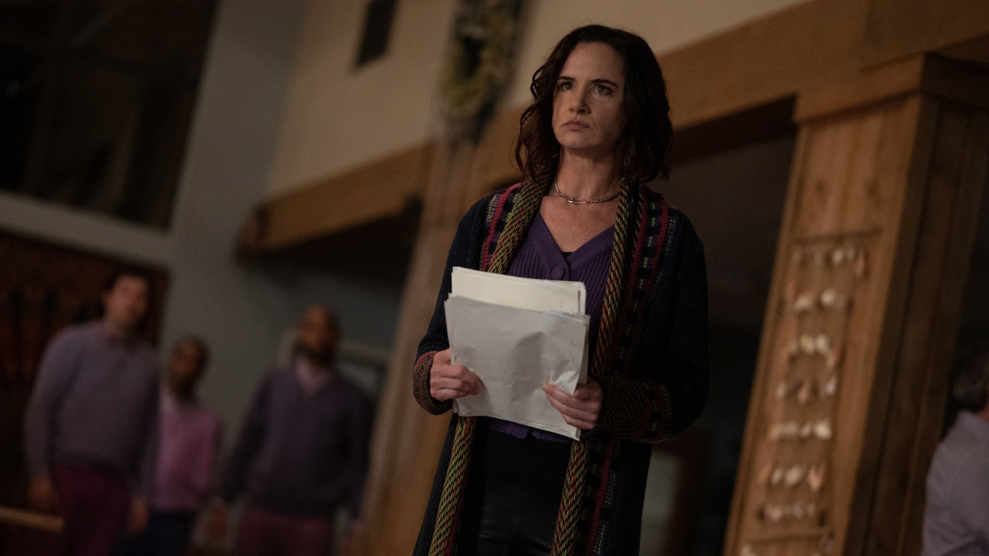 A woman dressed in purple holding a stack of papers.