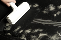 Person cleaning pet hair off car seat with ChomChom
