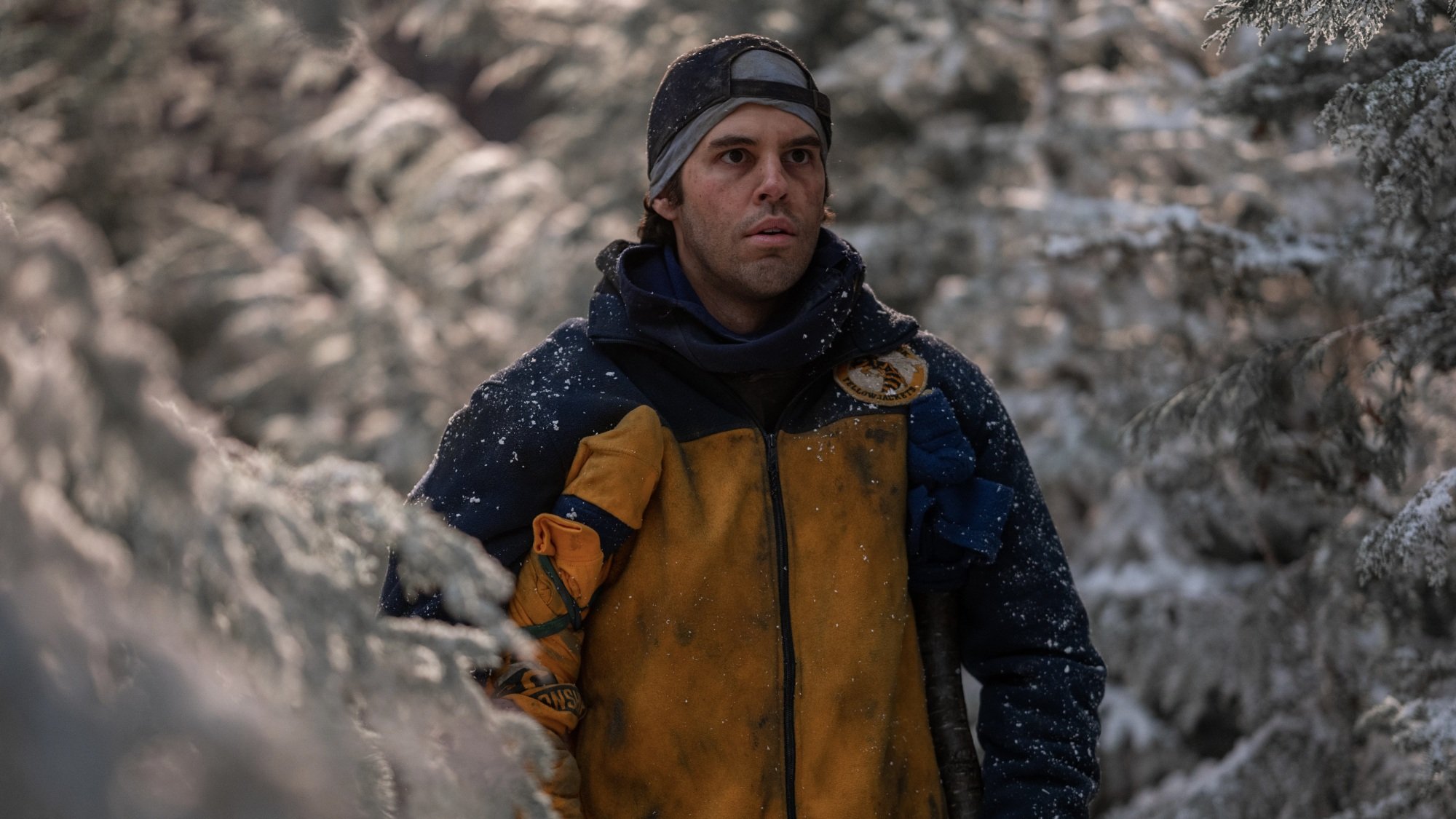 A man in crutches in a snowy forest.