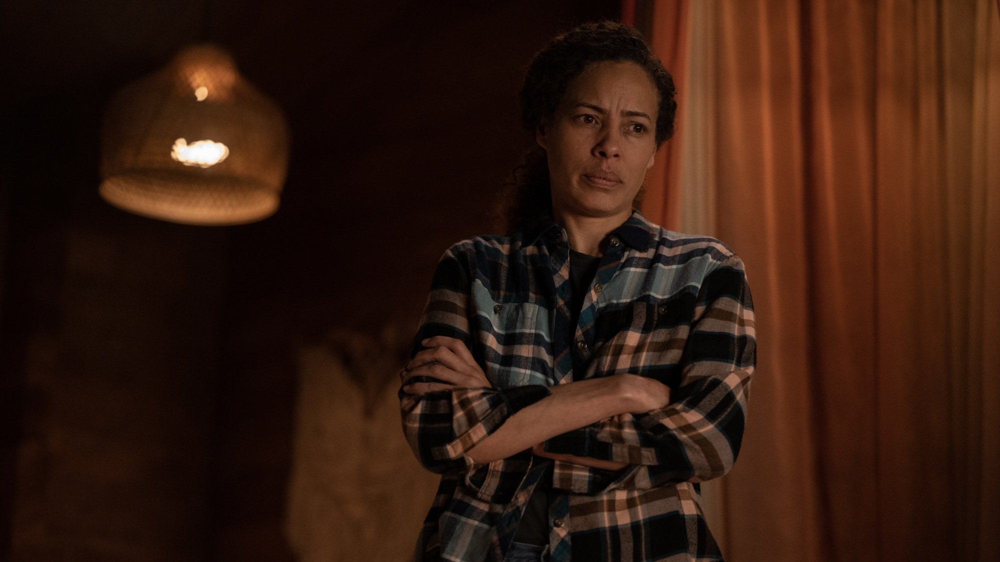 A woman in a flannel shirt crosses her arms.