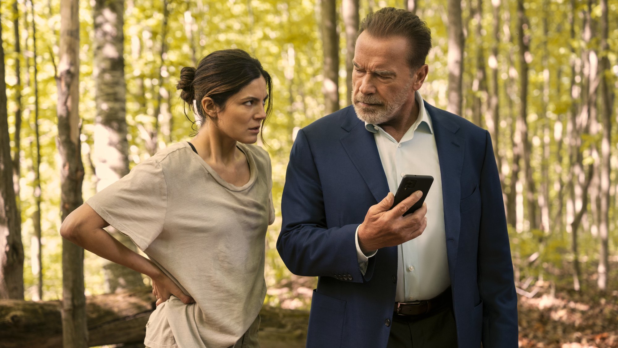 Two CIA agents stand in the woods looking at a phone in the film "FUBAR"