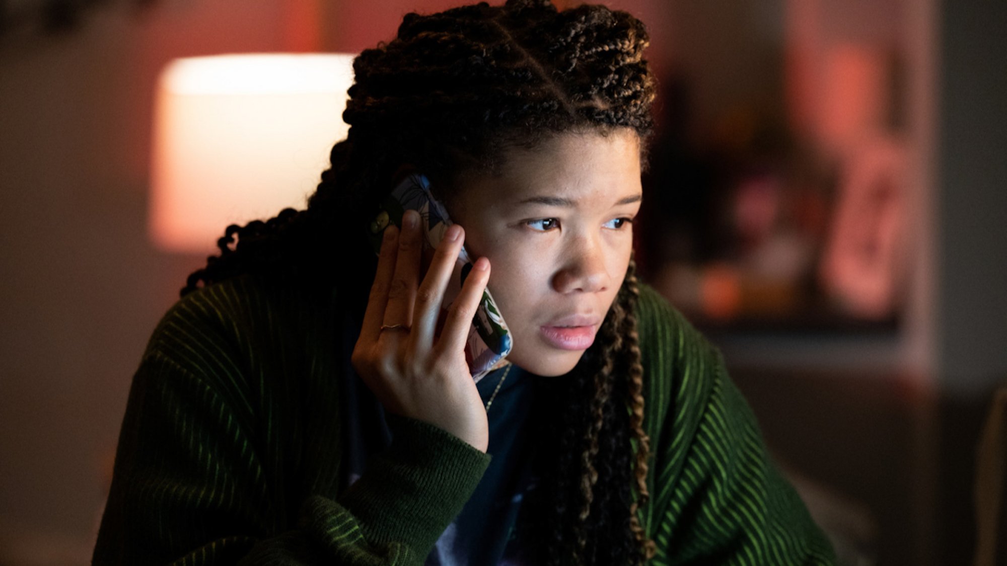 A teen girl works on a computer holding a phone in the movie "Missing"