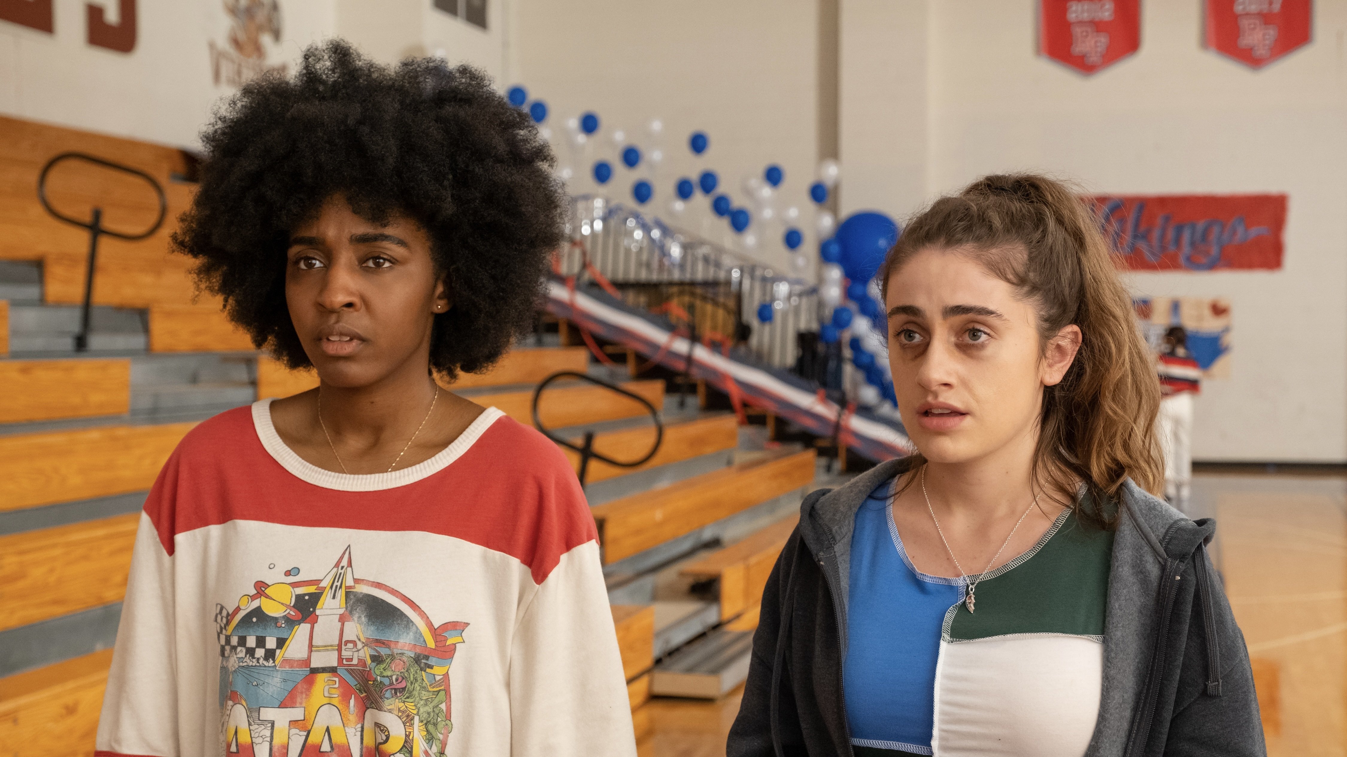 Two young women with bruised faces standing in a high school gym.