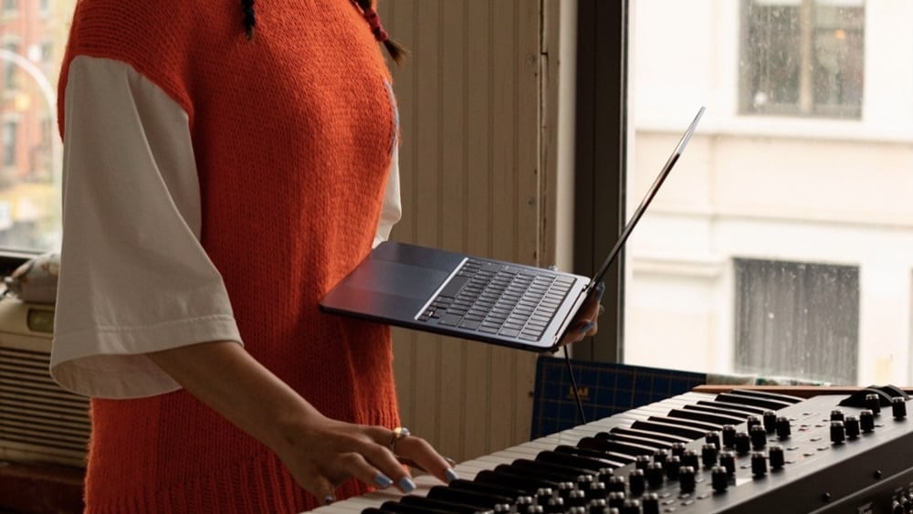 person holding m2 macbook air in front of a piano