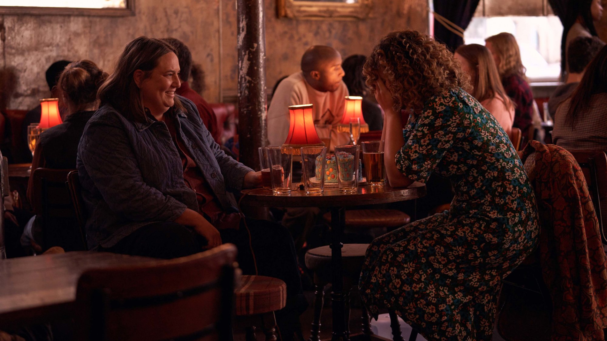 "Starstruck" co-writers Alice Snedden and Rose Matafeo sit in a pub together, Matafeo's head in her heads, in the TV show.