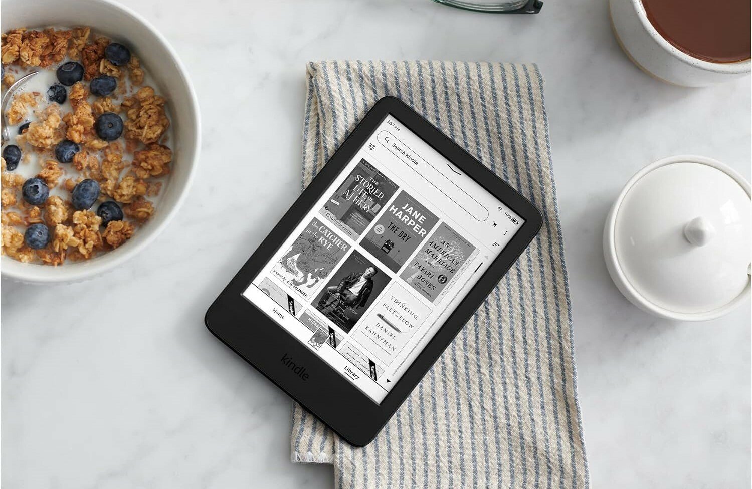 a kindle e-reader sits in a kitchen table next to a bowl of cereal