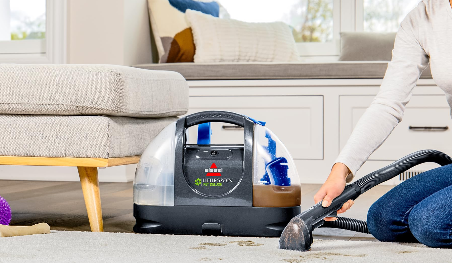 Person cleaning rug with Bissell Little Green Pet Deluxe upholstery cleaner