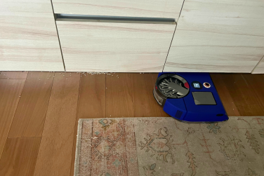 Dyson 360 Vis Nav robot vacuum cleaning up rice under kitchen cabinet
