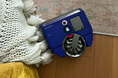 Dyson 360 Vis Nav robot vacuum cleaning rug beside blanket tassels and yellow chair