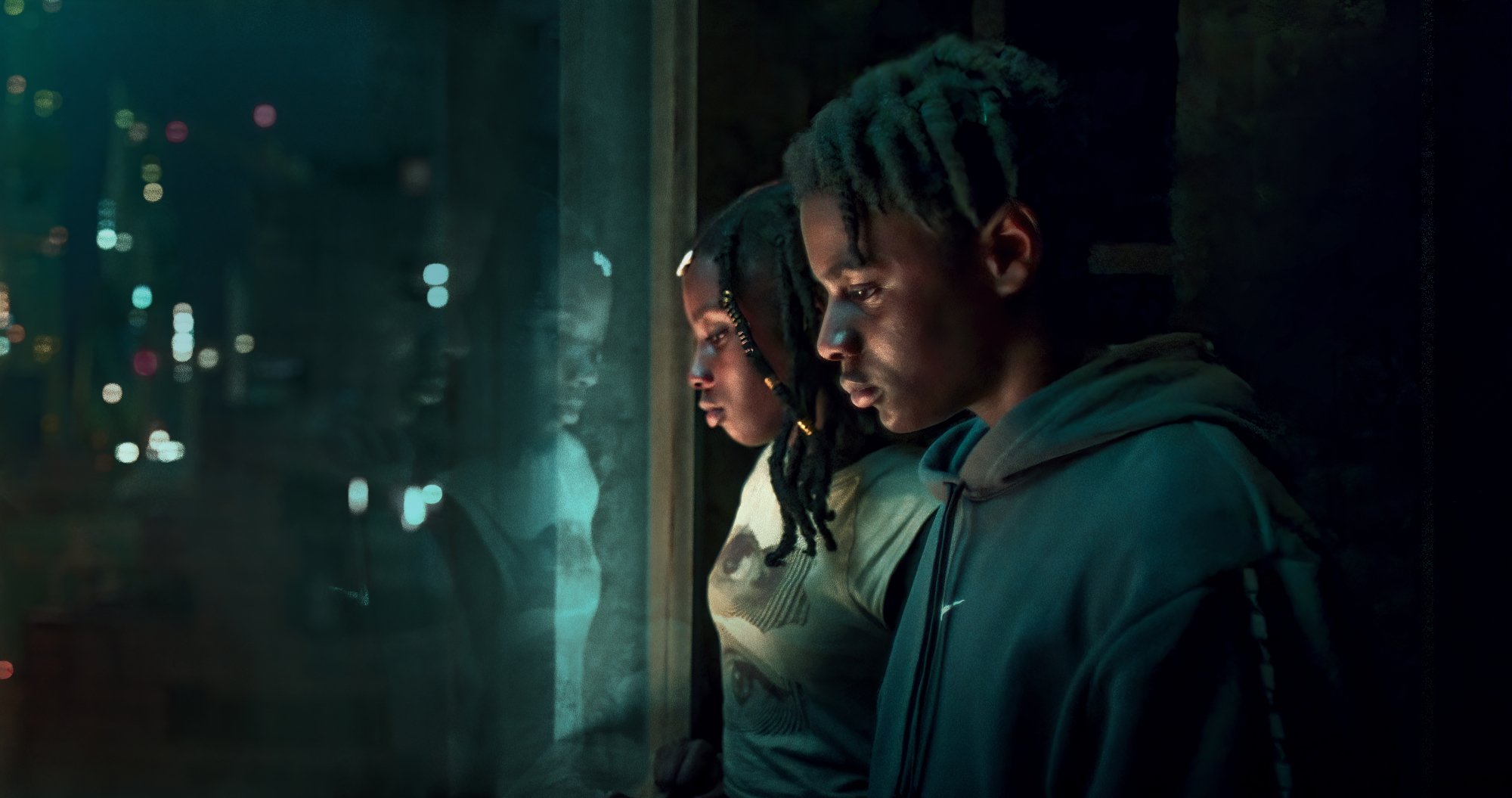 Two young Black people look out a window in "The Kitchen."