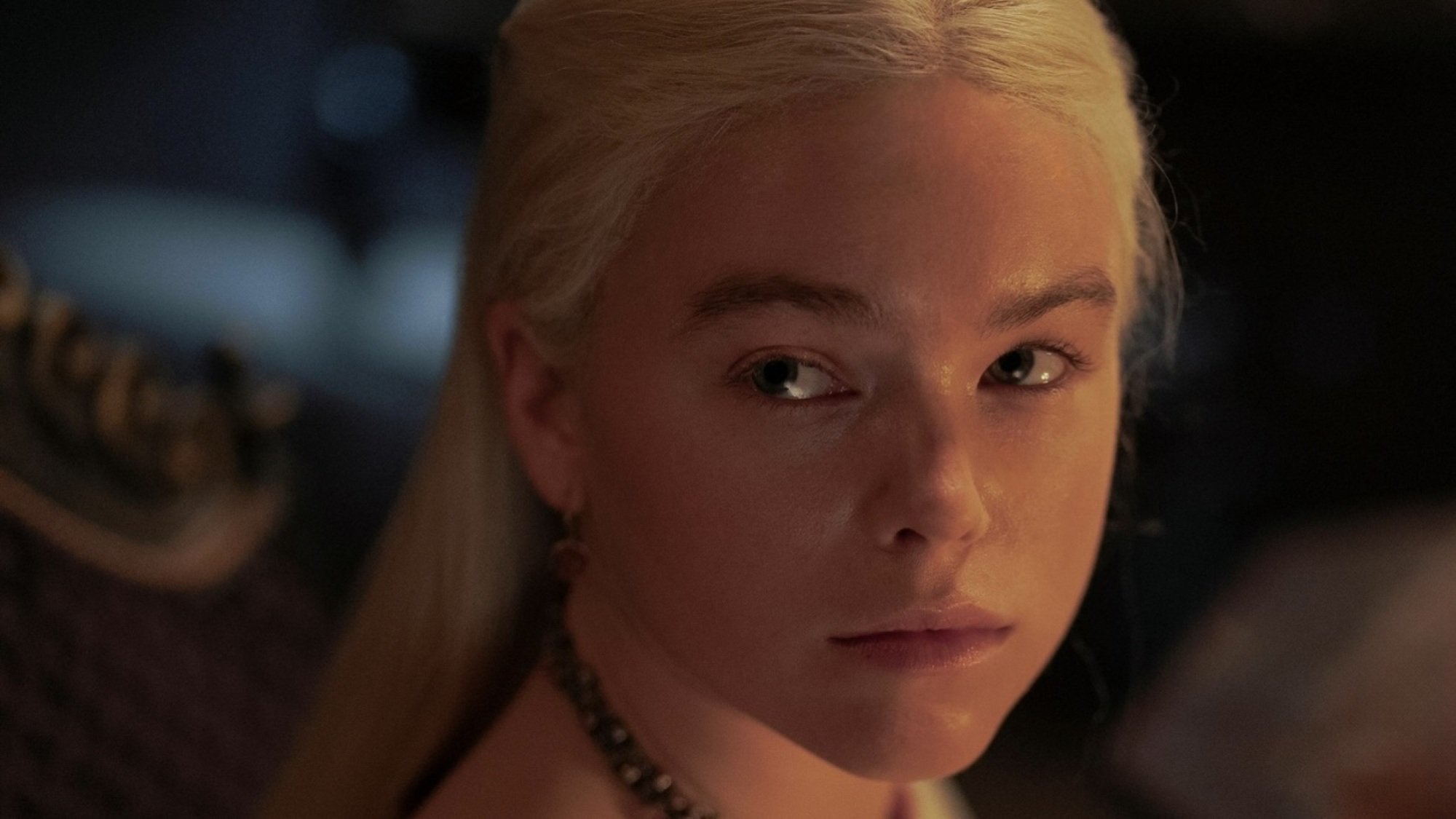 Close-up on young Rhaenyra Targaryen's face, lit by a fire from a nearby hearth.